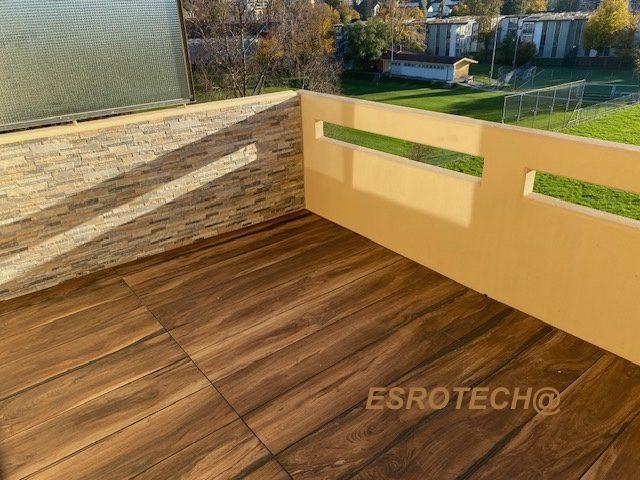 Balkon mit Belag in Holzoptik und Steinzierwand